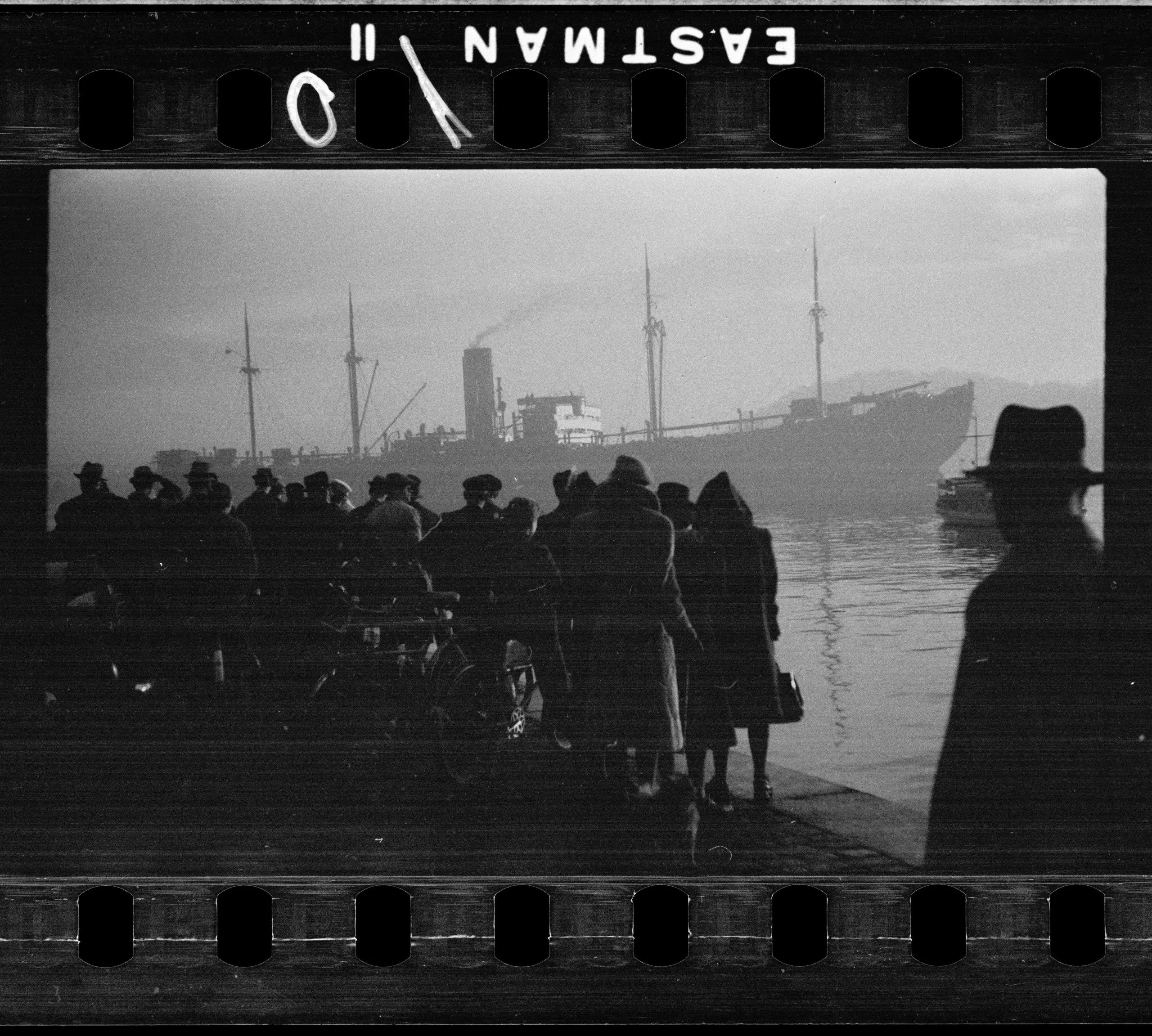 I förgrunden en grupp människor och i bakgrunden syns det nazityska skeppet SS Donau i Oslo hamn 1942.