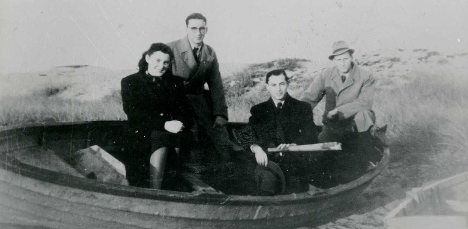 Fyra personer i en mindre båt tittar mot kameran.