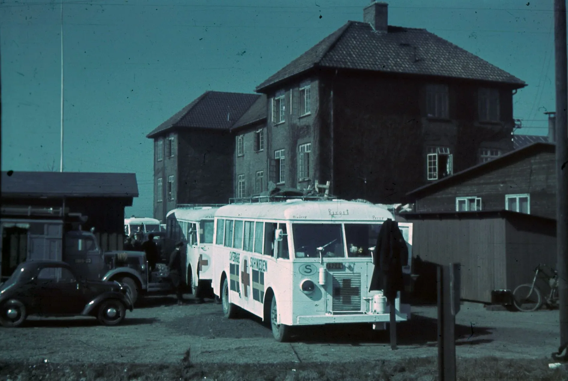 En vit buss parkerad mellan två hus.