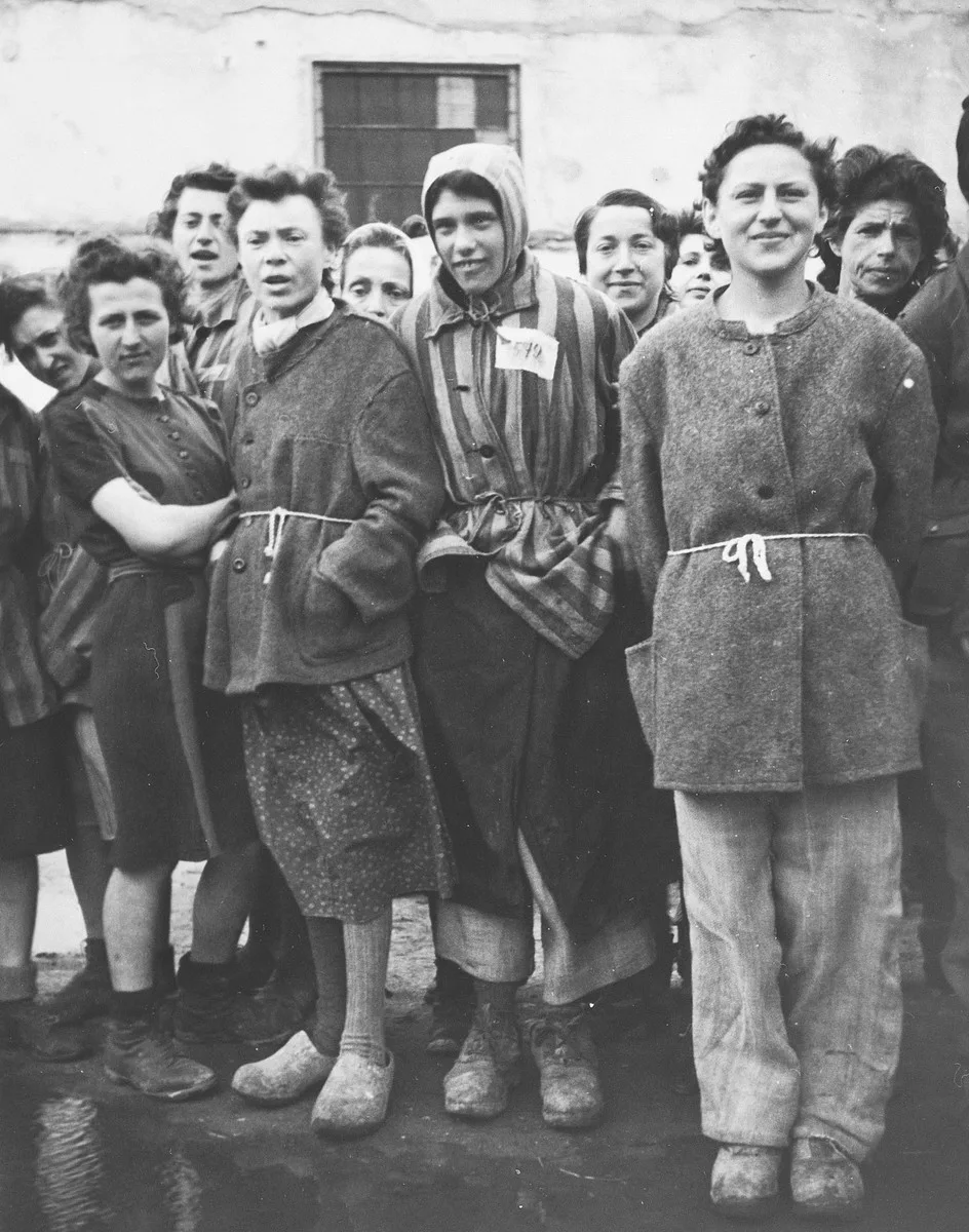 A group of female survivors stands outside a barracks in the newly liberated Lenzing concentration camp.