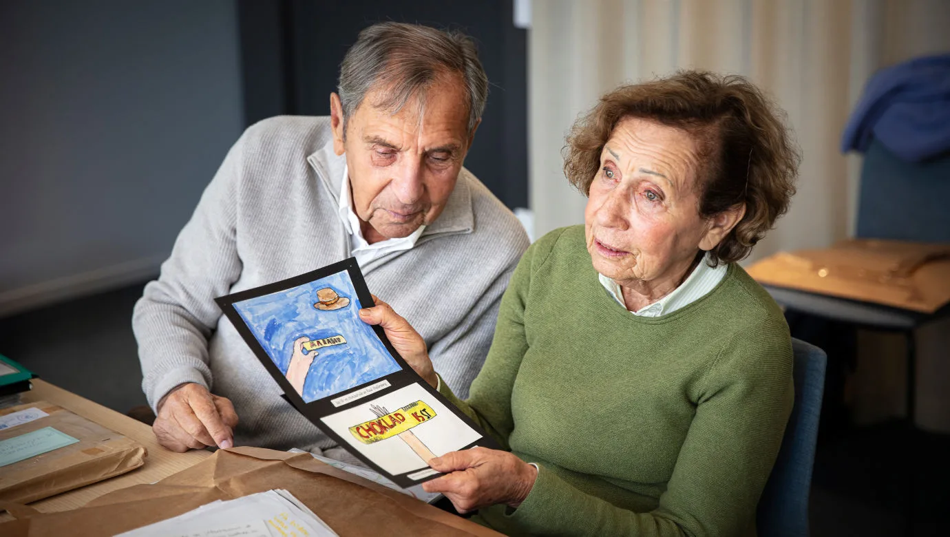 Jovan och Dina Rajs vid ett bord. Dina håller i teckningar.