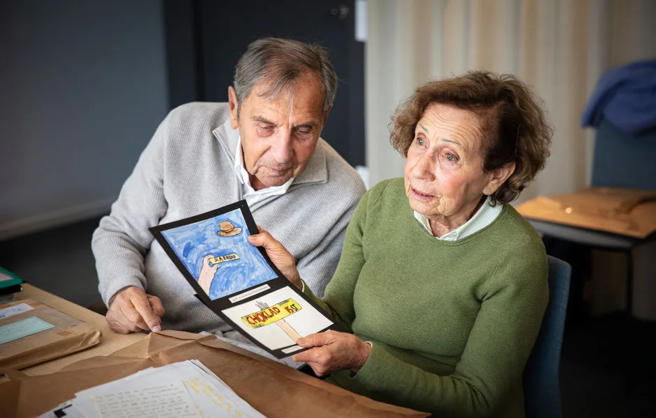 Jovan och Dina Rajs vid ett bord. Dina håller i teckningar.