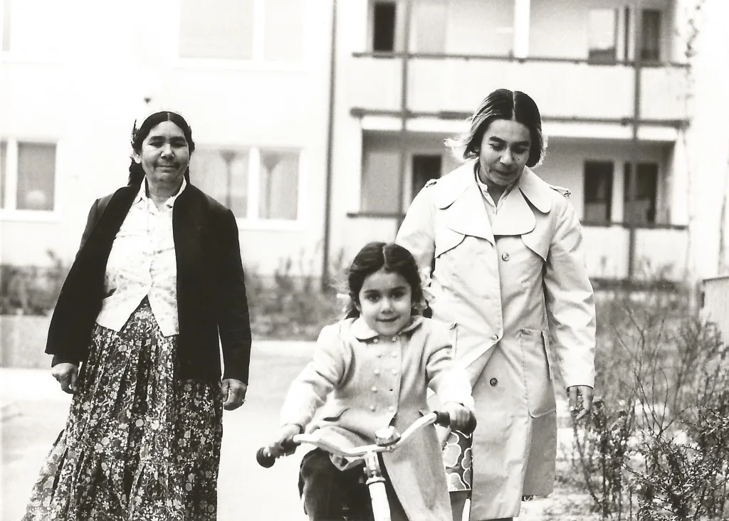 I förgrunden cyklar ett barn och två kvinnor går snett bakom henne.