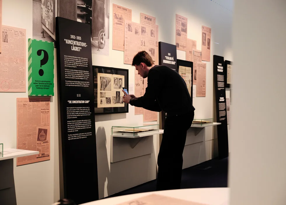 En person fotar med mobil i utställningen Svart på vitt.