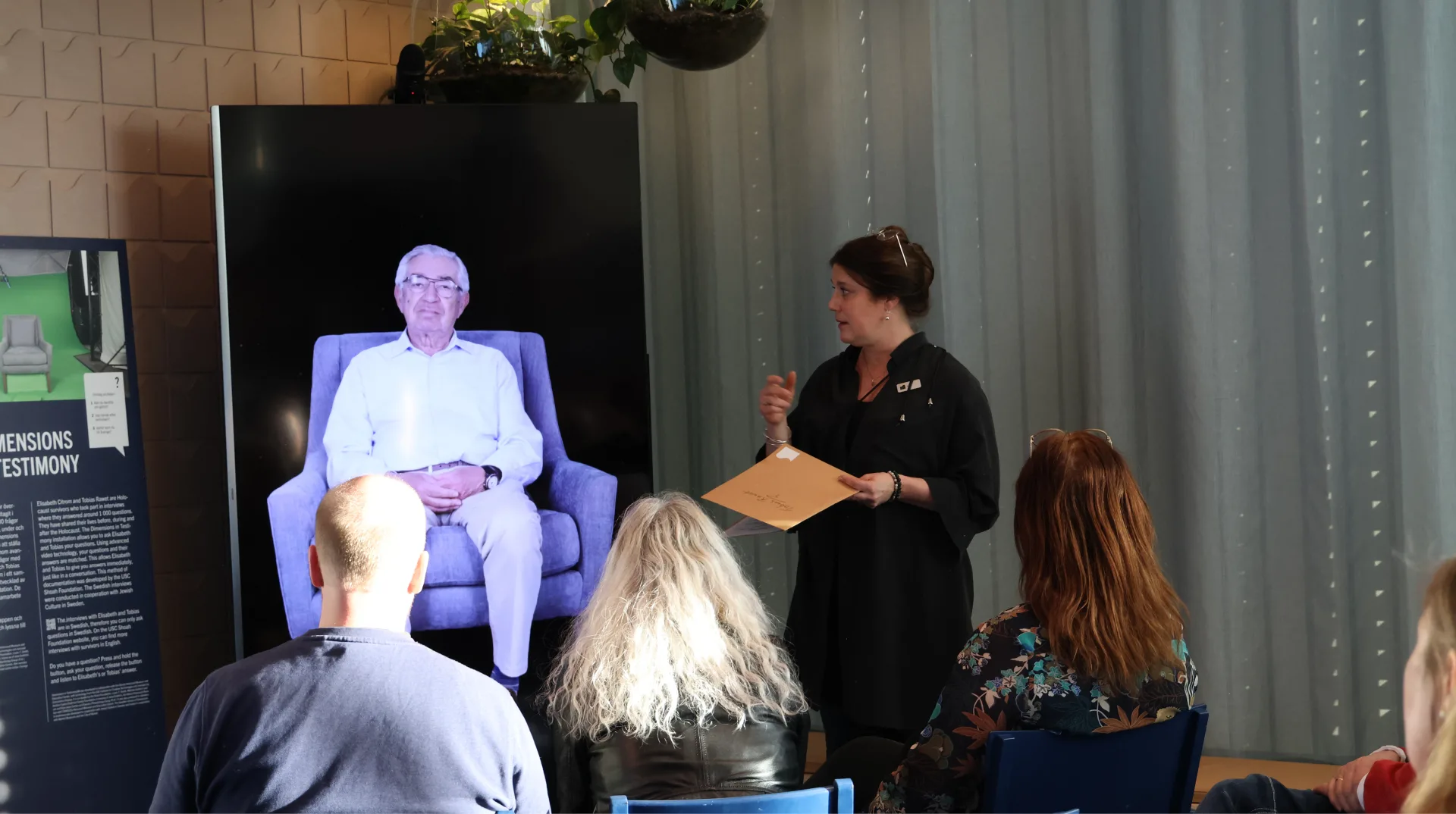 På en skärm syns Tobias Rawet, museets pedagog håller en visning av Dimensions in Testimony.