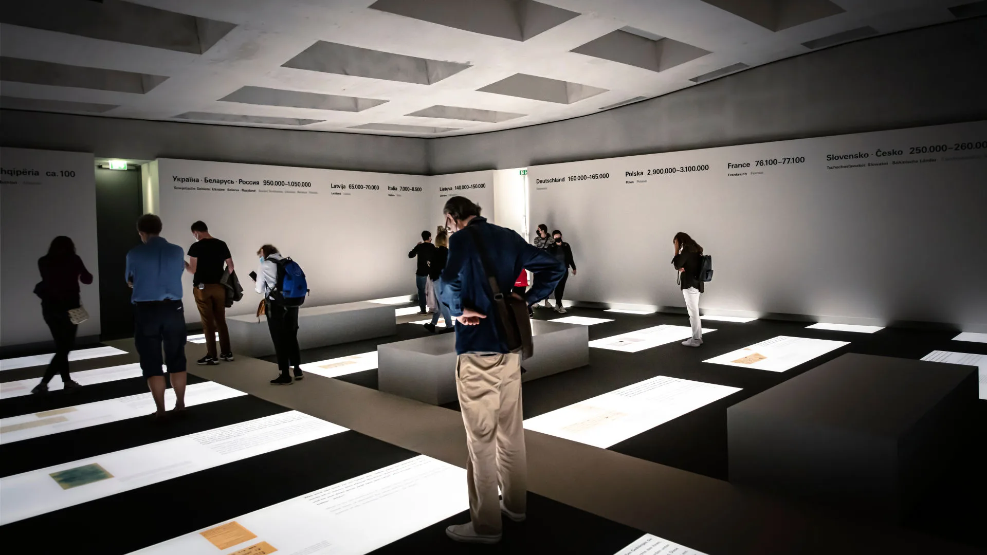 Besökare står i informationscentret under Monument över Europas mördade judar i Berlin. De läser på skyltar.