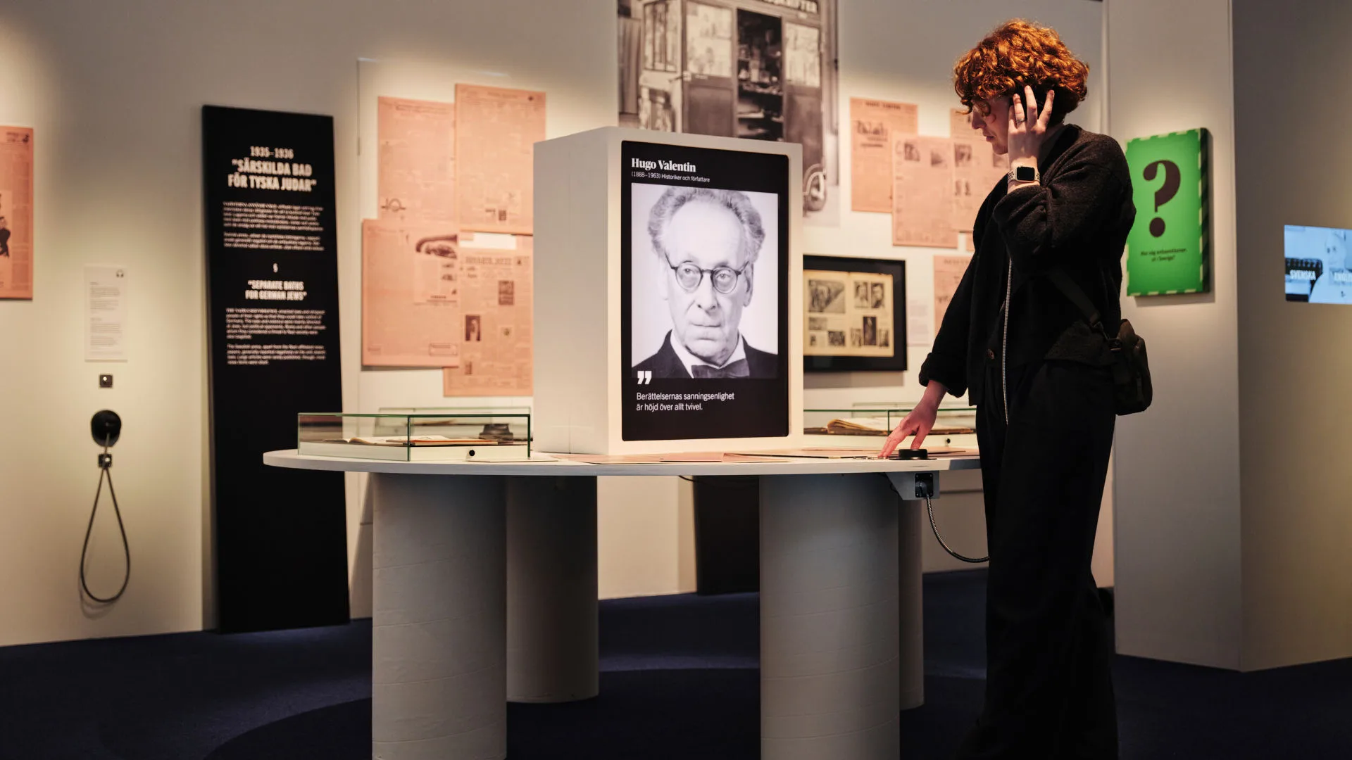 En person lyssnar i en hörlur i utställningen Svart på vitt.