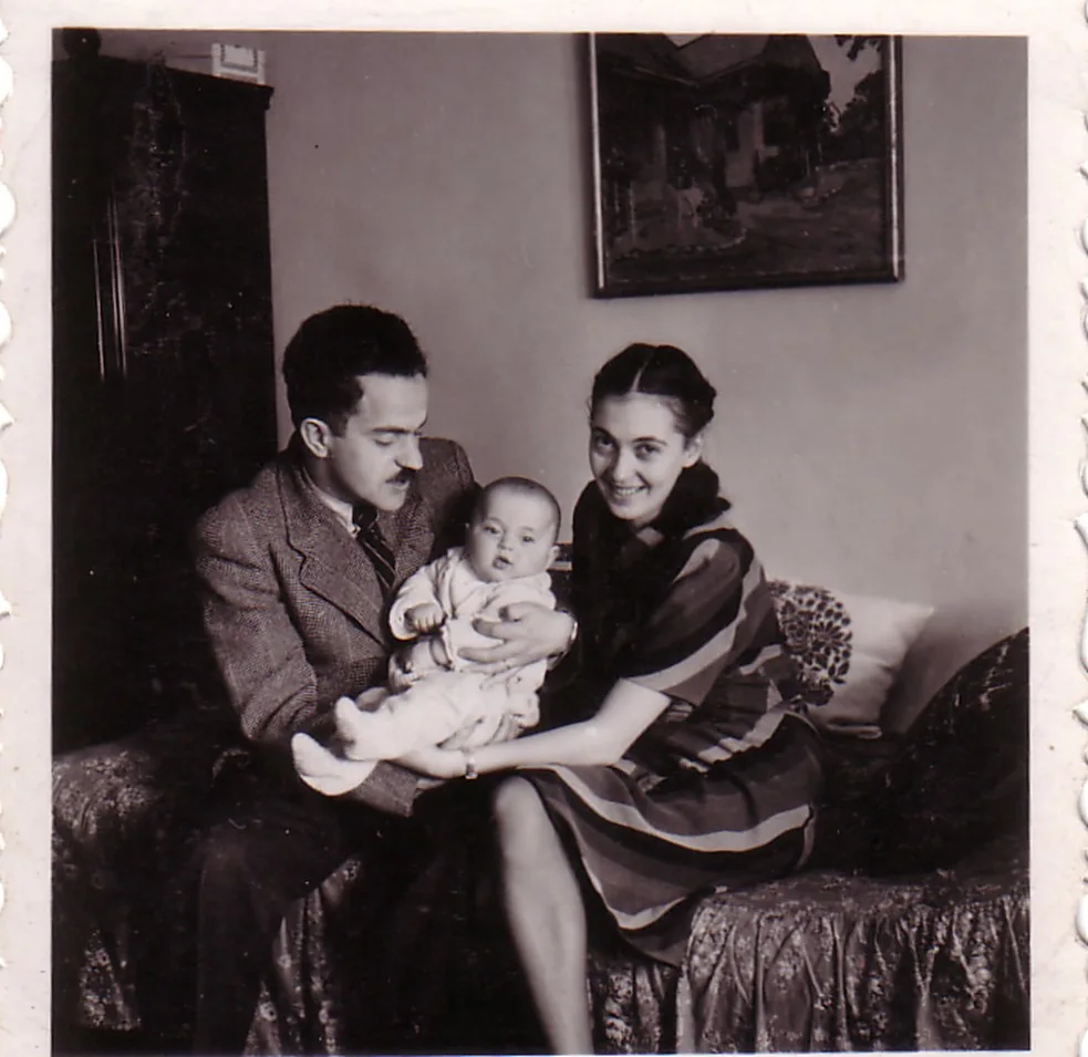 Svarvitt familjefoto av Miklós och Vera med Júlia från1941. De sitter i sängen och håller tillsammans i Júlia.
