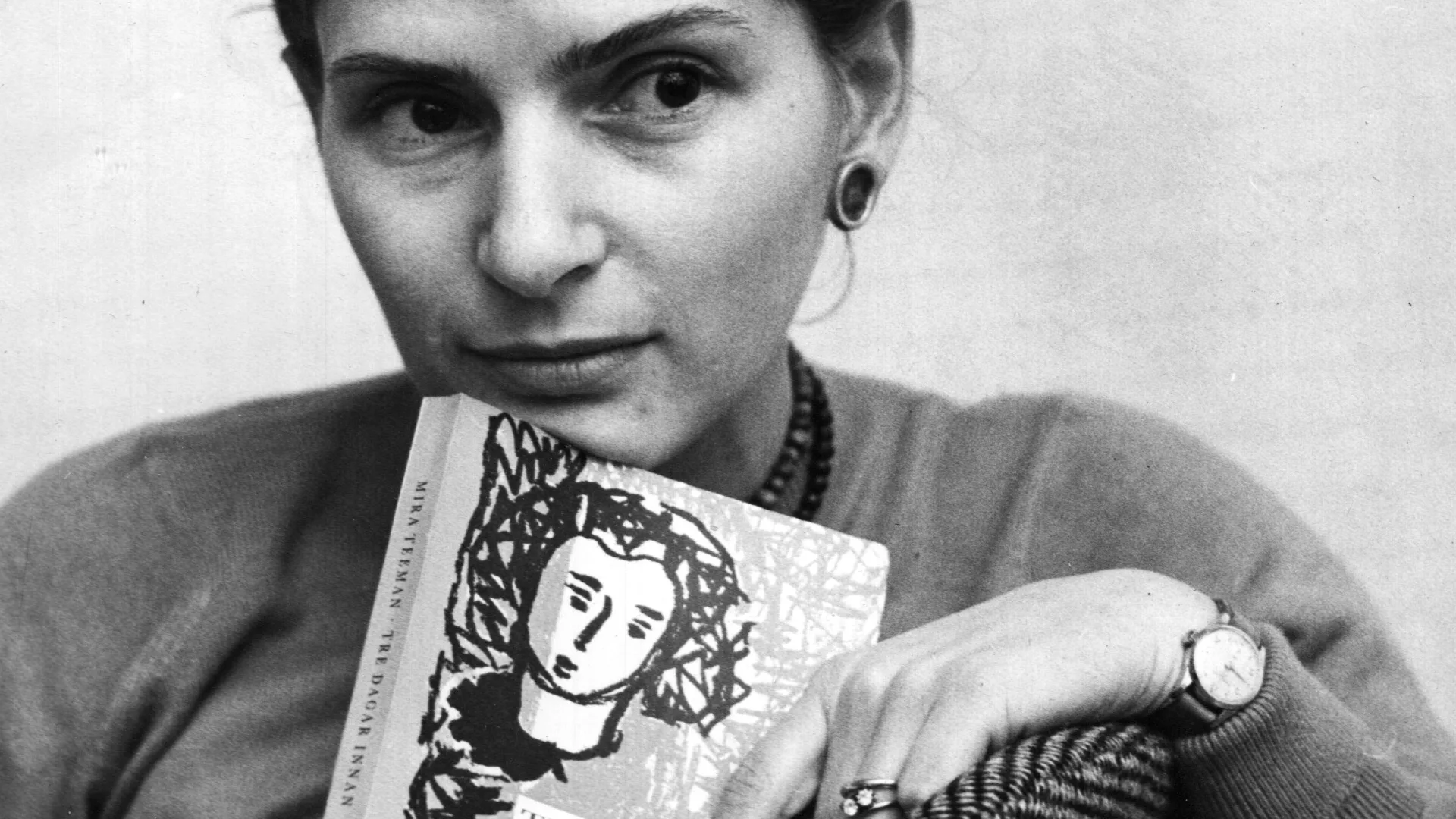 Svartvitt porträtt av kvinna som håller i en bok. 