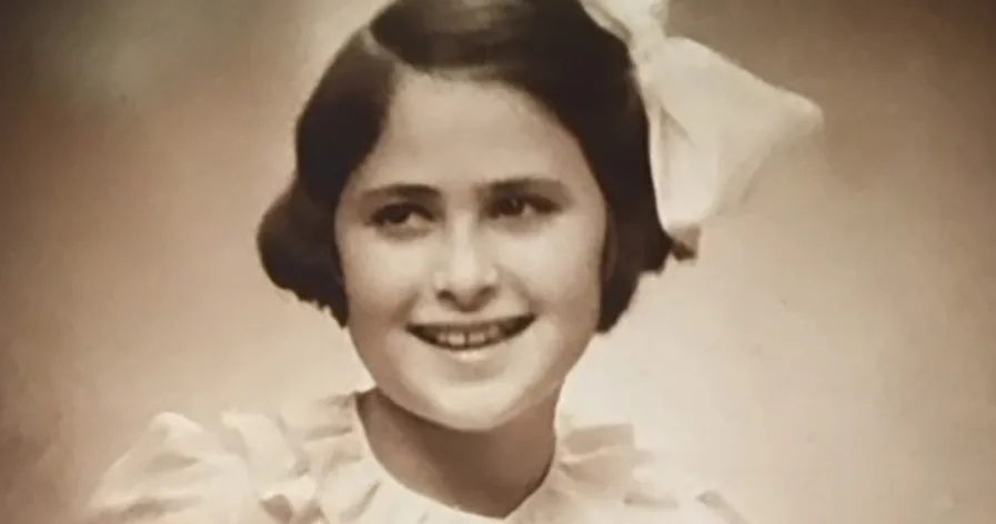 Svartvitt porträtt av Agi. Hon har vit klänning och vit rosett i håret.