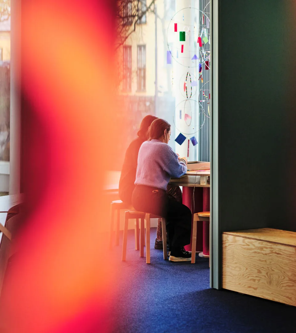 Två besökare sitter vid ett bord i en utställning på museet.